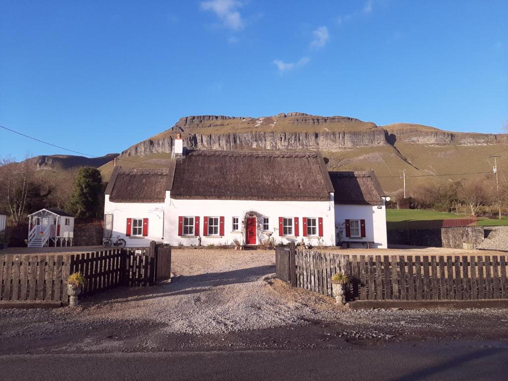 a white house with a fence in front of a hill at Willow Cottage Accommodation in Sligo