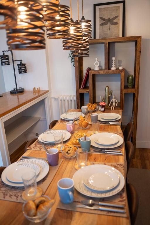 - une table en bois avec des assiettes et de la vaisselle dans l'établissement Moderne lumineux centre ville et plage à 5 min Proche place Strasbourg, à Brest
