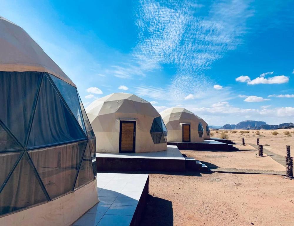 a group of three domed tents in the desert at Desert Eyes Camp in Wadi Rum