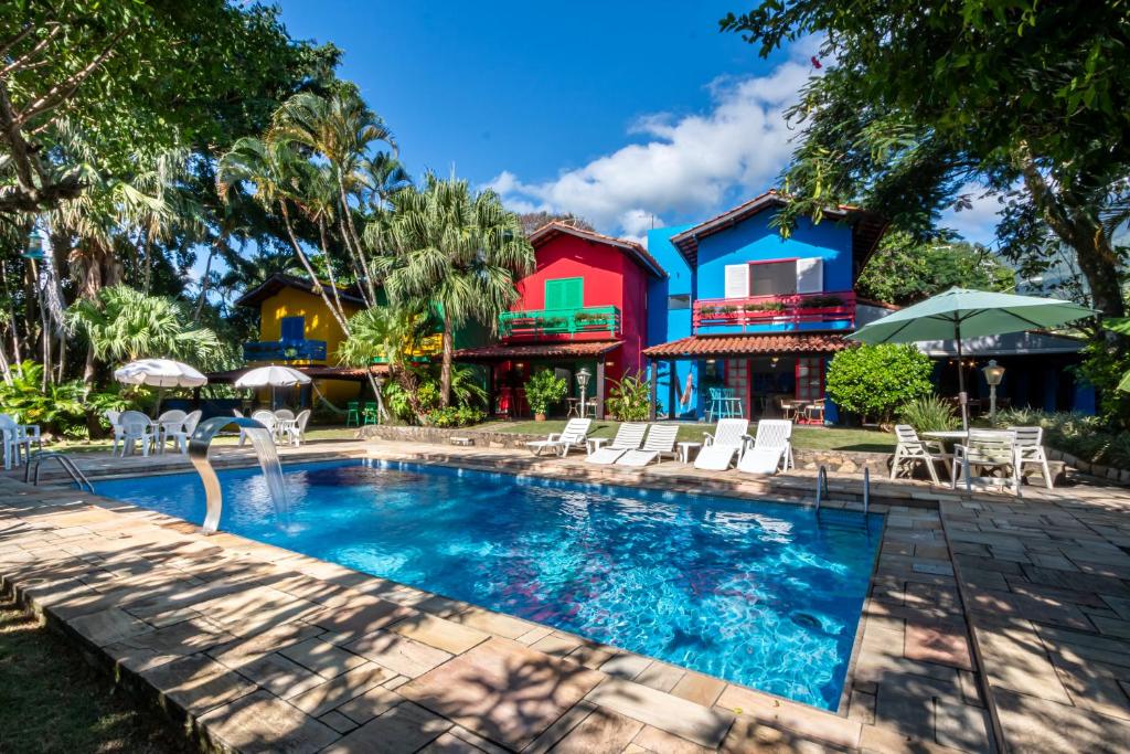 uma piscina com cadeiras e uma casa em Positano Ilhabela Lodges em Ilhabela