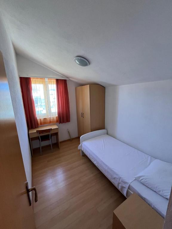 a bedroom with a bed and a desk and a window at Apartmani Šaldi in Pakoštane