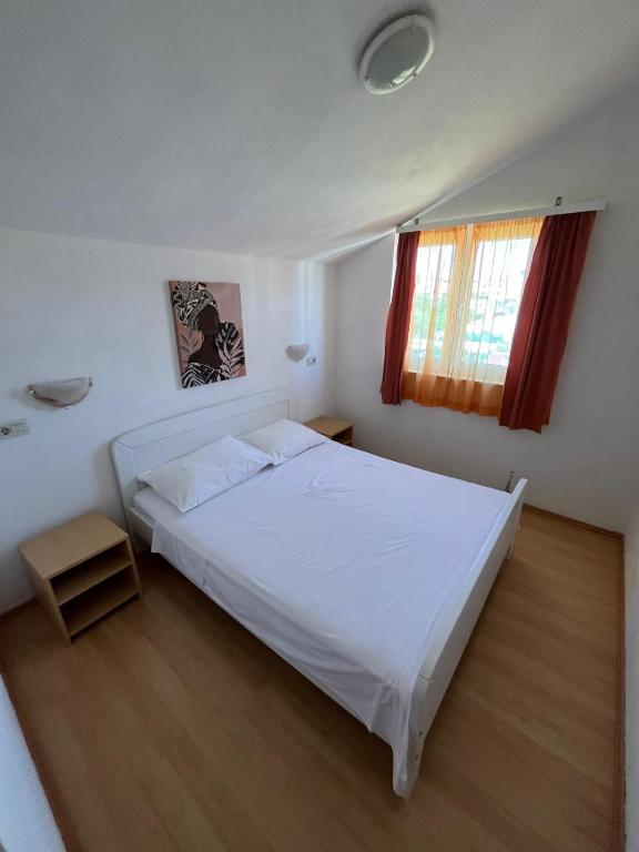 a bedroom with a white bed and a window at Apartmani Šaldi in Pakoštane