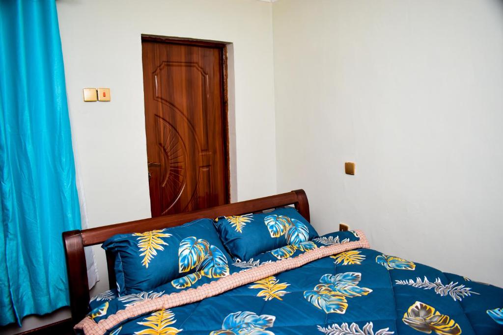 a bedroom with a bed with blue sheets and a wooden door at ndush home in Rutara