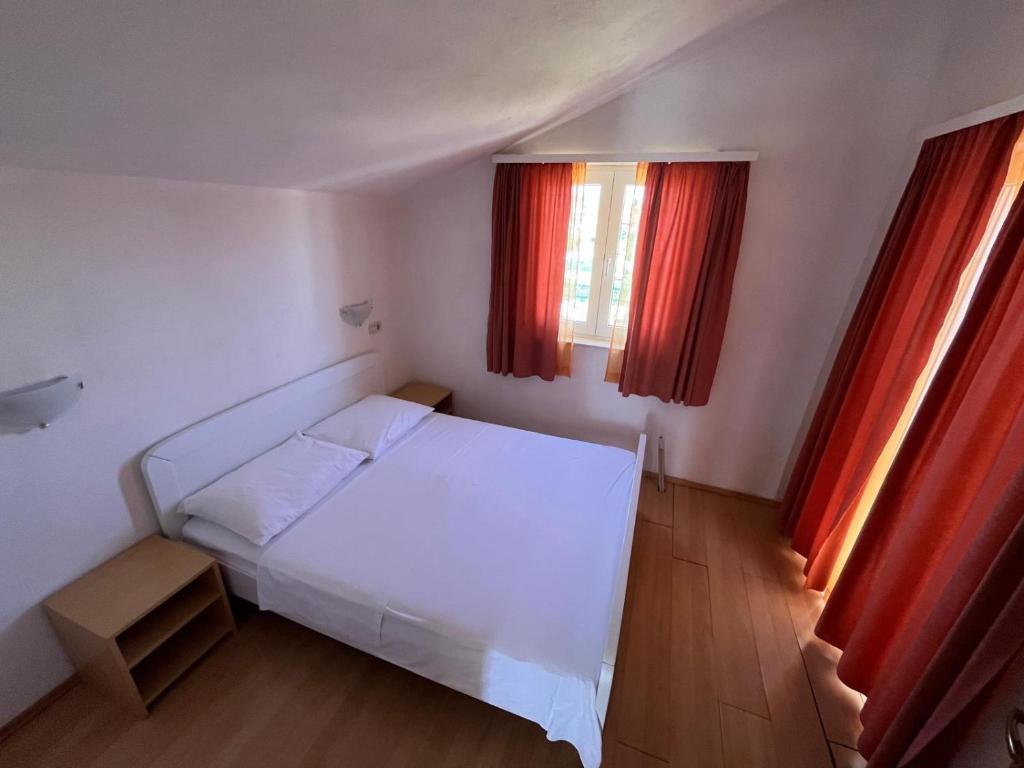 a bedroom with a white bed and two windows at Apartmani Šaldi in Pakoštane