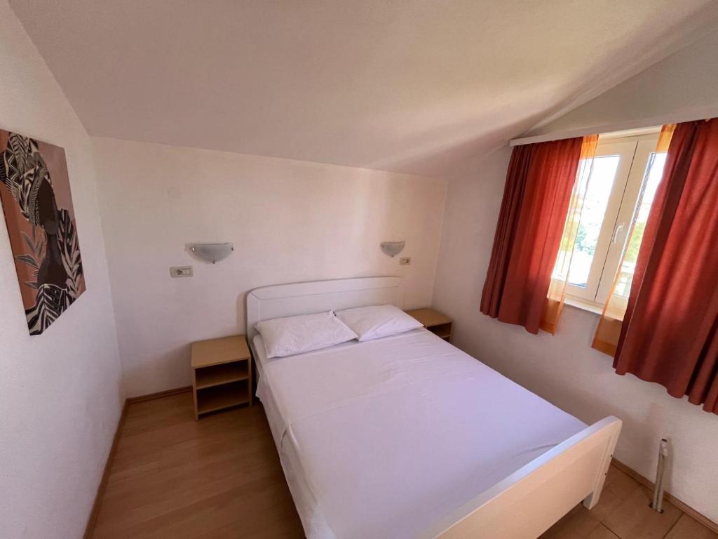 a bedroom with a white bed and a window at Apartmani Šaldi in Pakoštane