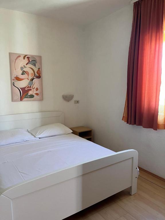 a white bed in a room with a window at Apartmani Šaldi in Pakoštane