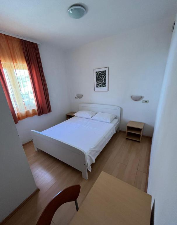 a bedroom with a white bed and a table at Apartmani Šaldi in Pakoštane