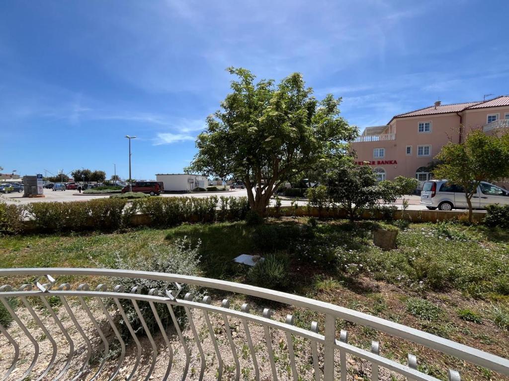 a white rail next to a tree and a building at Apartmani Šaldi in Pakoštane