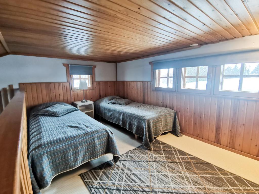 庫薩莫的住宿－Talvijärven Helmi，配有木墙和窗户的客房内的两张床