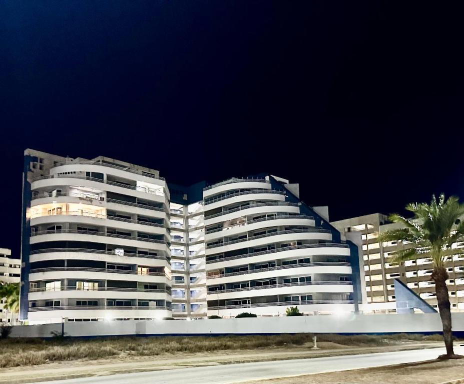 a large white building with a palm tree in front of it at Apartamento Isla de Margarita,Porlamar, Pampatar in Porlamar