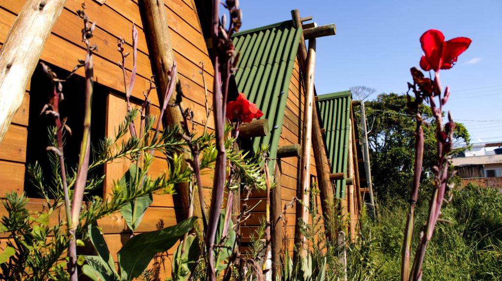 a wooden fence with red flowers in front of a building at Valhalla Glamping House in Bombinhas