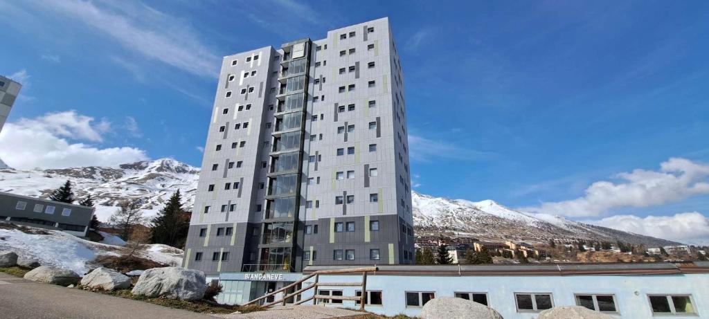 wysoki biały budynek z śnieżnymi górami w tle w obiekcie HIGH ALTITUDE Apartment w mieście Passo del Tonale