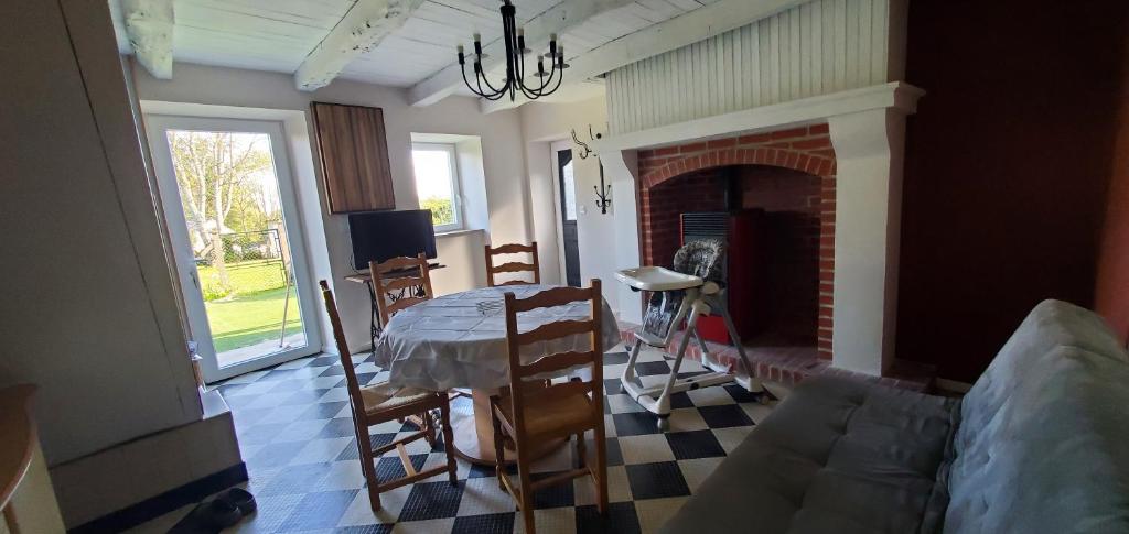Una sala de estar con una mesa y una chimenea. en Location petite maison, en Ambazac