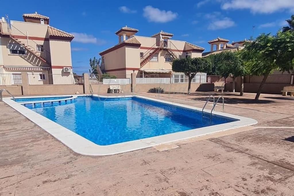 a swimming pool in front of a house at Agréable appartement avec piscine commune in San Pedro del Pinatar