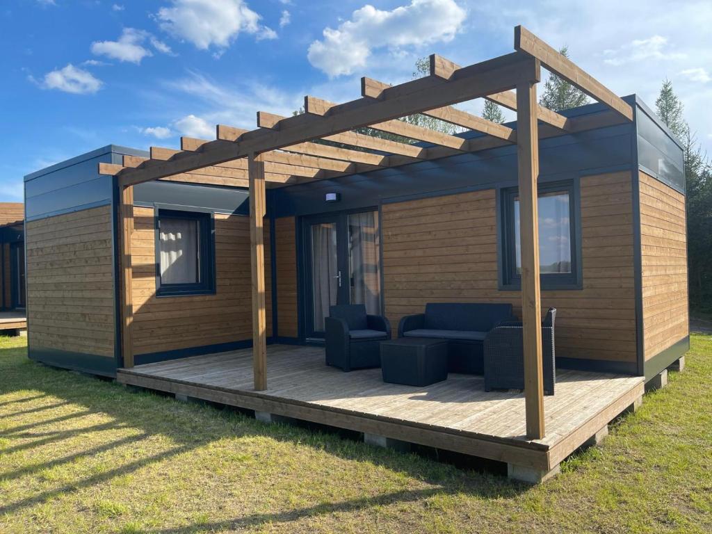 a house with a wooden deck with a pergola at Przytulny domek na Mazurach - Jeziorowskie k. Kruklanek in Jeziorowskie
