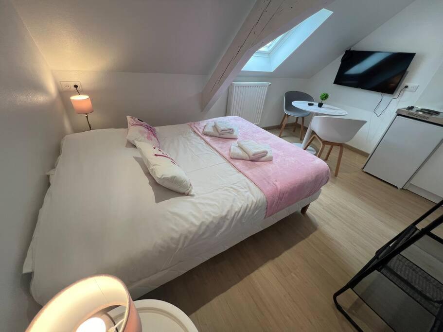 - une chambre avec un lit avec des oreillers et une table dans l'établissement Esprit France, joli studio au coeur de Mulhouse, à Mulhouse