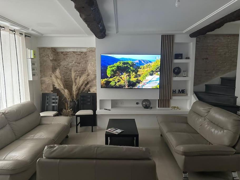 sala de estar con sofá y TV de pantalla plana en La Verdière, en Cesny-Bois-Halbout