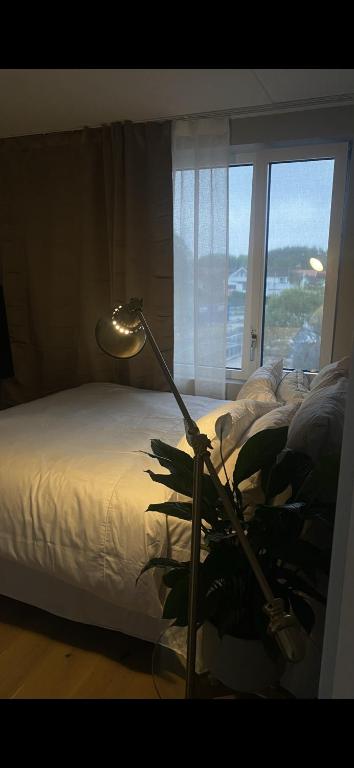 una lampada accanto a un letto con finestra di Leilighet a Larvik