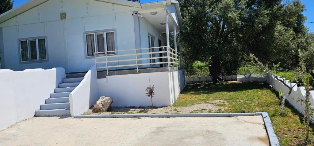 ein weißes Haus mit Treppen und einem Zaun in der Unterkunft Villa Ermis in Dhërmi