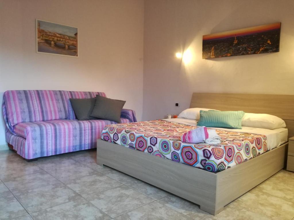 een slaapkamer met een bed en een bank bij Home Signa Via Roma 26 in Signa