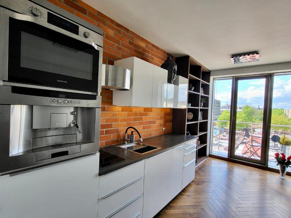 a kitchen with white cabinets and a tv on the wall at Salwator Apartment - Topolove Rooms & Apartments in Krakow