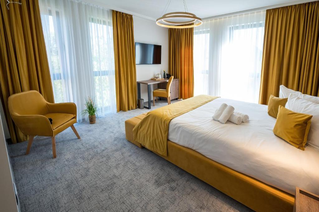 a bedroom with a large bed with a chair and a desk at ALIVE HOTEL in Oradea