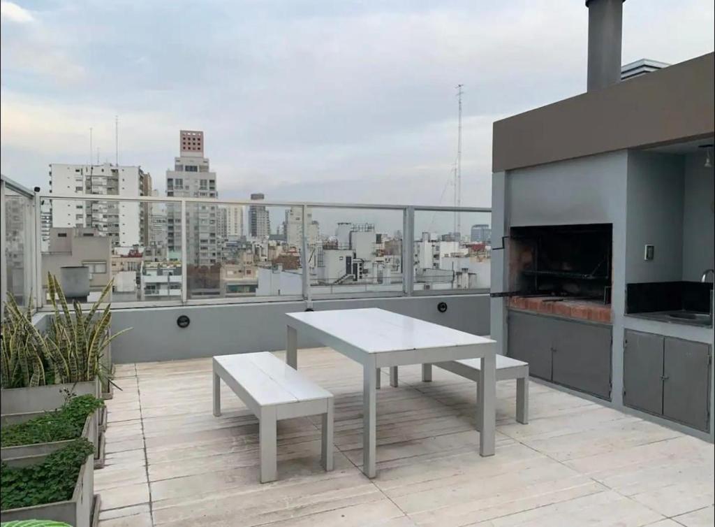 einen weißen Tisch und eine Bank auf einem Balkon mit Aussicht in der Unterkunft Exquisito 2 ambientes en Palermo Soho in Buenos Aires