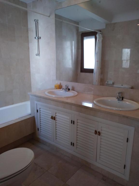 サアラ・デ・ロス・アトゥネスにあるAtico Duplex con magnificas vistasのバスルーム(洗面台2台、トイレ、バスタブ付)