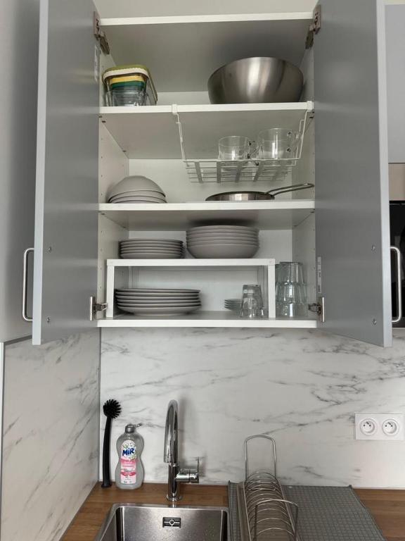 une cuisine avec un évier et de la vaisselle dans un placard dans l'établissement Studio Saint Cyr, à Saint-Cyr-lʼÉcole