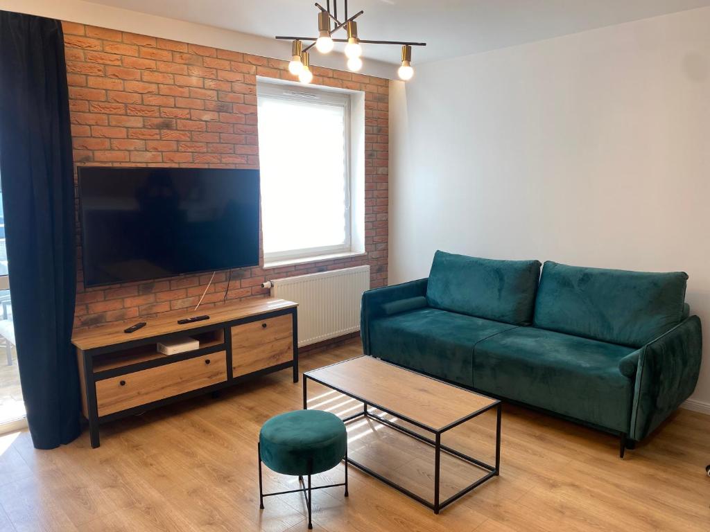 a living room with a green couch and a tv at ApartamentAugust in Zielona Góra