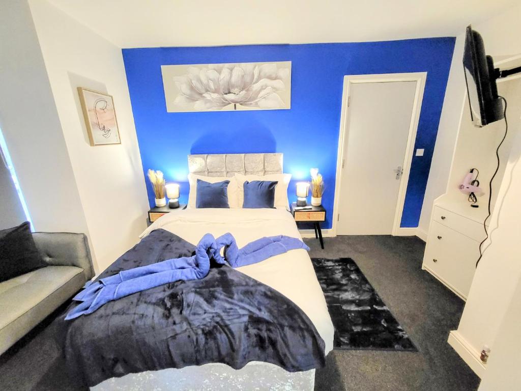 een slaapkamer met een groot bed met een blauwe muur bij Premier Nottingham Studios - Burford Road in Nottingham