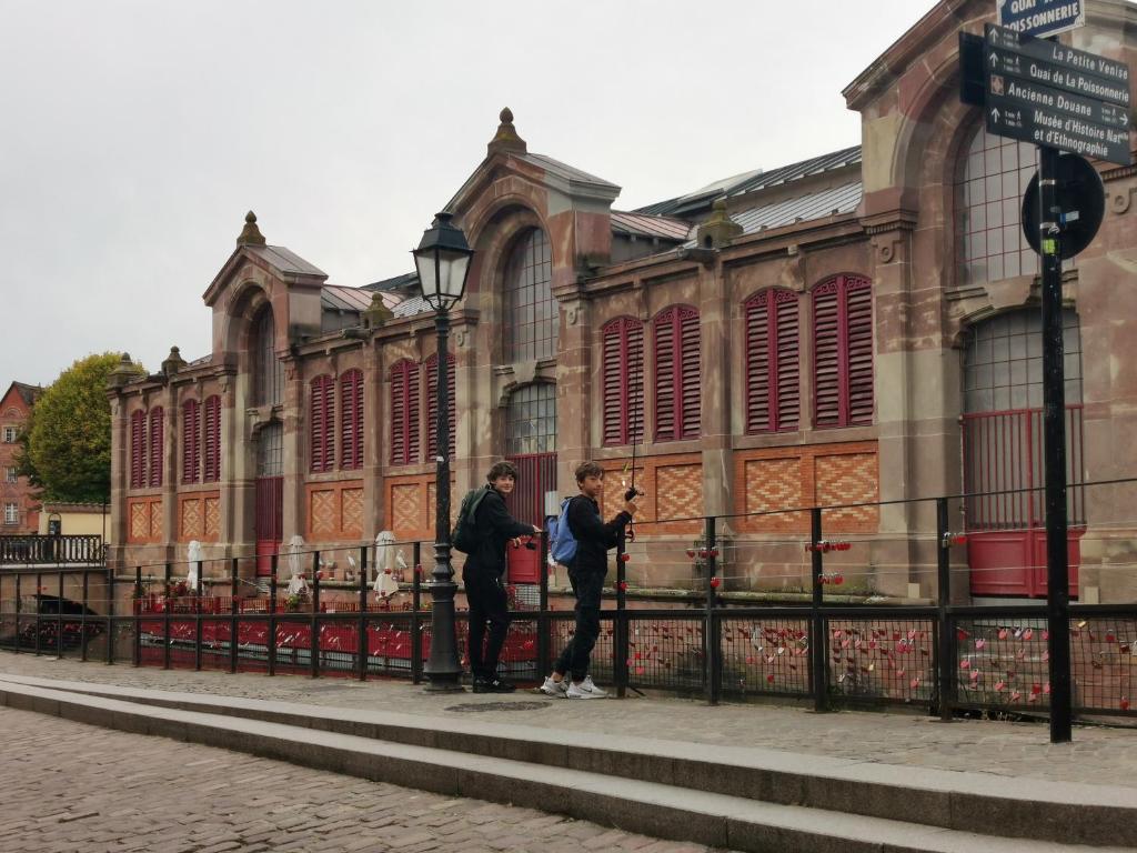 two people standing on a fence in front of a building at Chambre dans appartement in Colmar