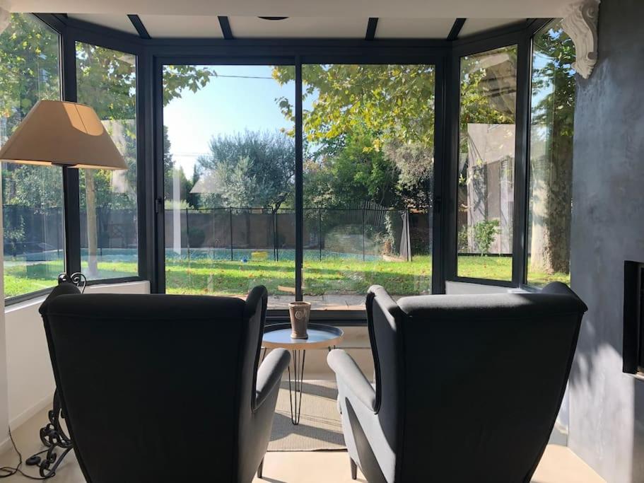 uma sala de estar com 2 cadeiras, uma mesa e janelas em Magnifique Villa avec Piscine em Aix-en-Provence
