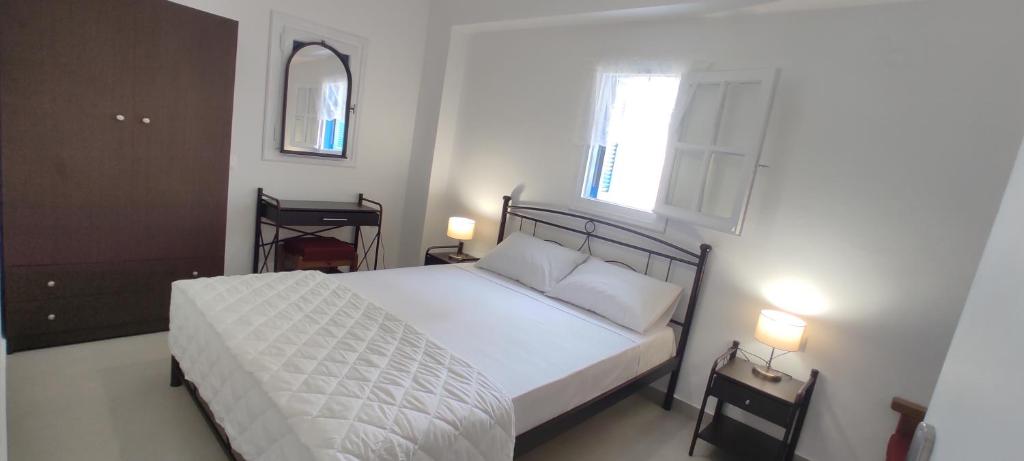 1 dormitorio con cama blanca y ventana en Φωλιά en Olympos
