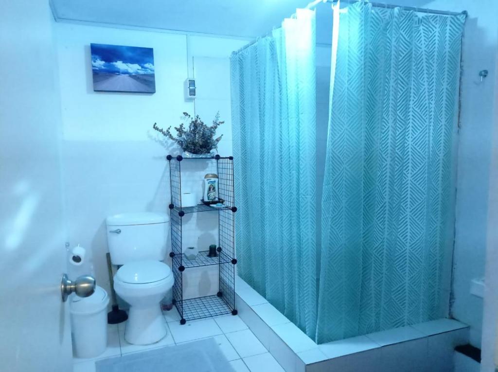 y baño con cortina de ducha azul y aseo. en Linda habitación cerca al mar, en Lima