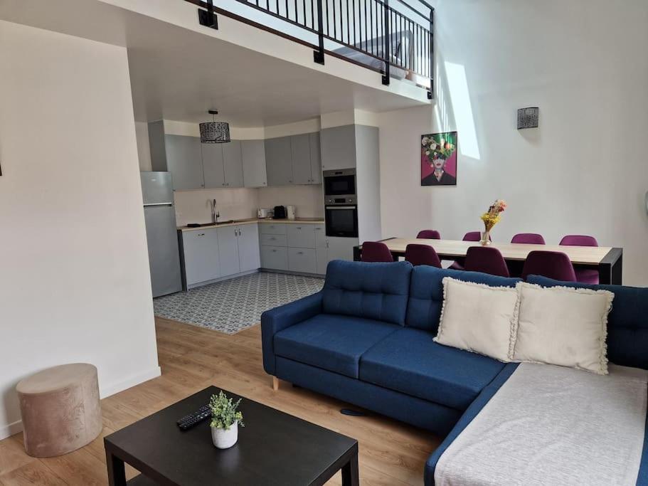 un salon avec un canapé bleu et une cuisine dans l'établissement WD Saint Roch - Appartement Duplex 202 - Métro 7 Proche Paris, à Villejuif