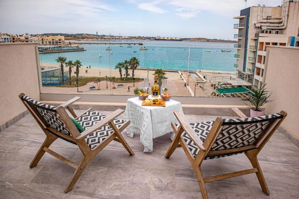 a table on a balcony with a view of the ocean at Birzebbuga -Two Bed Penthouse in Birżebbuġa