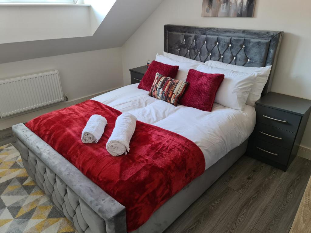 a bedroom with a large bed with red pillows at SAV Apartments Nottingham Road Loughborough - 2 Bed Apartment in Loughborough