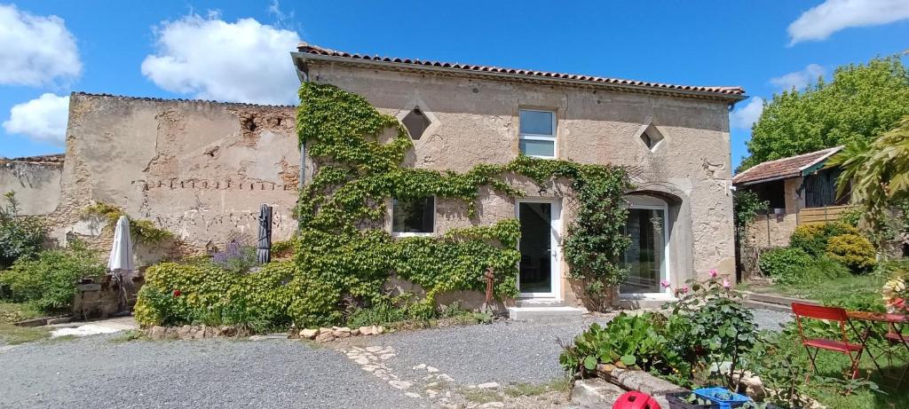 un viejo edificio con hiedra a un lado. en Maison Irondas, en Saint-Pierre-dʼAurillac