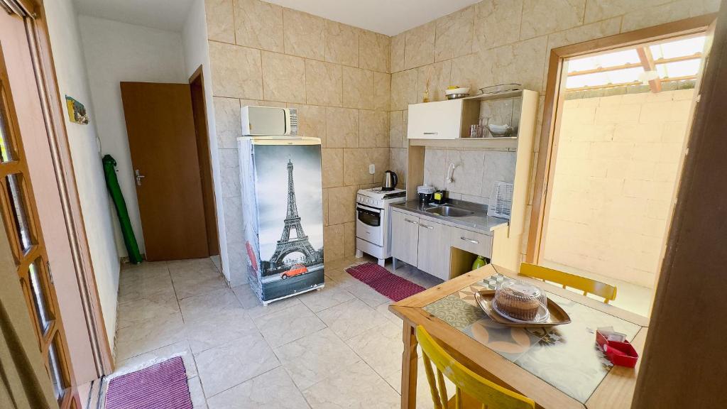 een keuken met een koelkast en een foto van de eiffeltoren bij Bella Praia apartamento Girassol in Passo de Torres