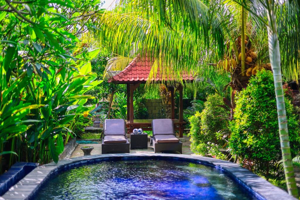 a backyard pool with two chairs and a gazebo at Asoka Bungalows in Nusa Penida