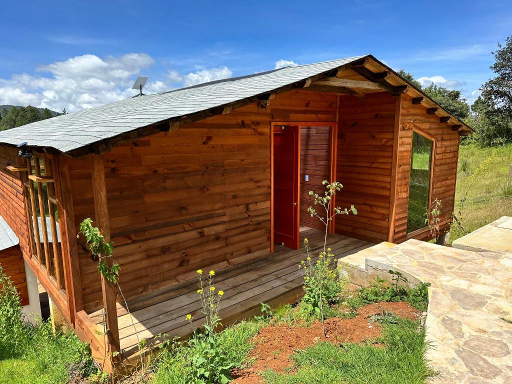 a small wooden cabin with a red door at Cabaña Magnolia in Nuevo León