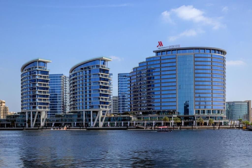 trois grands bâtiments devant une masse d'eau dans l'établissement Marriott Marquis Dubai, à Dubaï