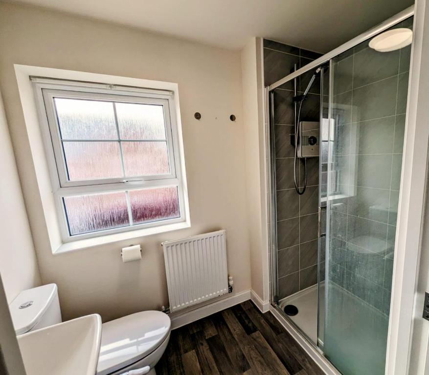 a bathroom with a shower and a toilet and a window at Modern Comfy 3 Bed Home - Free 2 space driveway and free road parking in Derby
