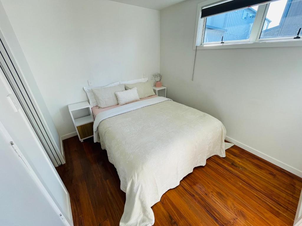 Habitación blanca con cama y ventana en Sunny Modern Cottage - Close to Airport, en Napier