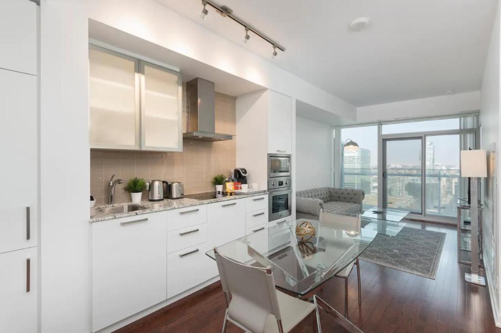 uma cozinha com uma mesa de vidro e armários brancos em Executive 1 BR Condo - CN Tower & City View em Toronto