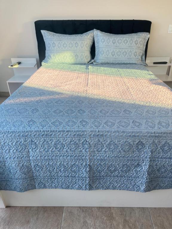 a bed with a blue comforter and two night stands at Central Praias III in Cabo Frio