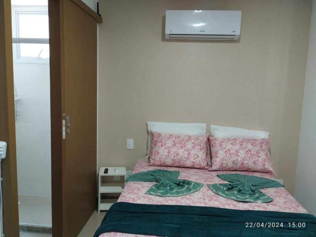 1 dormitorio con 1 cama con sábanas y almohadas rosas en 2 Quartos Novíssimo na Praia de Itaparica com PISCINA e SAUNA, en Vila Velha