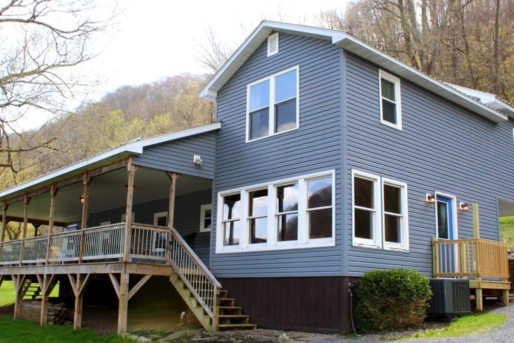 a blue house with a porch and a deck at Riverfront Property in NRG National Park near Sandstone Falls- Wi-Fi, Pet-Friendly in Hinton