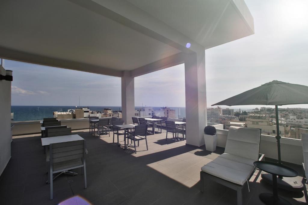 a balcony with tables and chairs and an umbrella at The Josephine Boutique Hotel in Larnaka